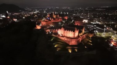 Gece gökyüzüne karşı aydınlatılmış Edinburgh Kalesi 'nin çarpıcı manzarasını keşfedin. Zengin tarih ve görkemli mimari aşağıdaki şehrin üzerinde büyüleyici bir atmosfer yaratıyor ve hayranlık uyandırıyor..