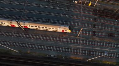 Alacakaranlıkta, sessiz bir tren geniş bir avluda tek başına duruyor, karmaşık raylarla çevrili. Solan ışık, o anın dinginliğini ve yalnızlığını vurgulayan sakin bir atmosfer yaratıyor..