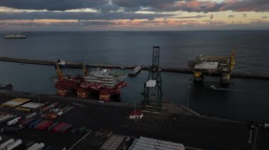 Tenerifes limanında konuşlanmış, okyanusun üzerinde güzel bir günbatımı tarafından çerçevelenmiş, hareketli denizcilik endüstrisini gözler önüne seren sondaj platformlarının büyüleyici etkinliğine tanık olun..