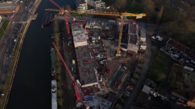 Canlı bir şehir manzarasında, büyük inşaat vinçleri, işçilerin büyük bir kalkınma sahasında gayretli bir şekilde ilerlemesi ile gökyüzüne hakim oluyor..