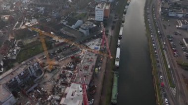 Canlı bir şehir manzarasının üzerinde, inşaat vinçleri malzemeleri manevra yapar ve geleceği şekillendirir. Bu dinamik proje, kentsel gelişim ve büyümeyi gözler önüne seren bir kanal boyunca devam ediyor..