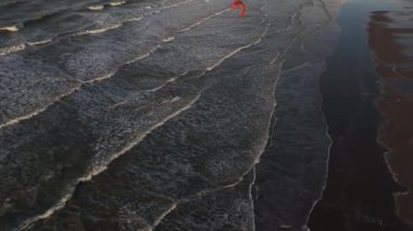 Şafak vakti dalgaların üzerinde zahmetsizce süzülen bir uçurtma sörfçüsünün heyecanını hissedin. Okyanus sabah güneşi altında büyüleyici desenler yaratırken ufuk ışıldar..