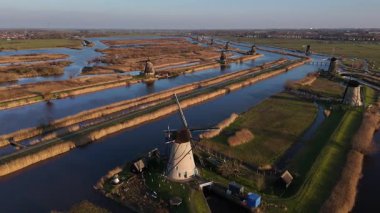 Kinderdijk yel değirmenlerinin büyüleyici güzelliğine tanık olun. Canlı bir günbatımına karşı dimdik duruyorlar. Sakin su yolları bu ikonik Hollanda manzarasının zengin tarihini ve kültürünü yansıtıyor..