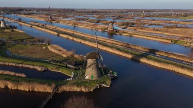 İkonik Kinderdijk yel değirmenlerinin yemyeşil ve sakin sularla çevrili ufuk çizgisini şereflendirdiği güzel bir dünyaya adım atın. Hollanda mirasına barışçıl bir bakış.