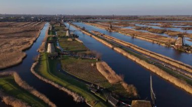 Kinderdijk yel değirmenlerinin altın gün batımına karşı görkemli bir şekilde ayakta duran nefes kesici manzaralarını keşfedin. Sakin sular ve yemyeşil yeşillikler bu ikonik manzarayı çevreleyip barışı çağrıştırıyor..