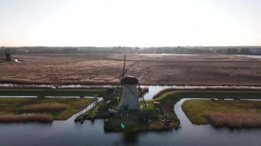 Kinderdijk 'in sakin manzarasını ikonik yel değirmenleriyle gün batımının sıcak renklerine karşı görkemli bir şekilde ayakta durun. Doğal ortam ve yumuşak sular barışçıl bir ortam yaratır..