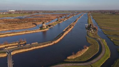 Kinderdijk 'in sakin manzarasını keşfedin. Orada görkemli yel değirmenleri gün batımına karşı dimdik dururlar. Sakin sular, bu ikonik yapıları yansıtarak pitoresk bir atmosfer yaratır..