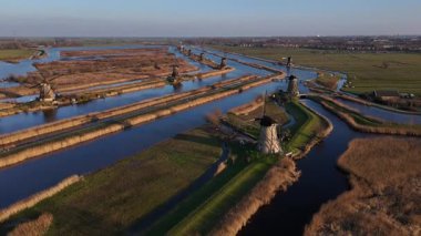 Alacakaranlık Kinderdijk 'in üzerine çöktüğünde ikonik yel değirmenleri titreyen gökyüzüne karşı dimdik dururlar. Yansımaları sakin sularda parıldar..