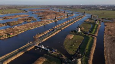Alacakaranlık çökerken Kinderdijk 'in dingin güzelliğini hissedin, ikonik yel değirmenlerinin üzerine sıcak bir parıltı saçın. Huzurlu su yolları büyüleyici manzarayı yansıtıyor, cezbedici yansımayı..