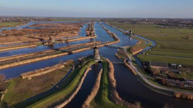 Alacakaranlık Kinderdijk 'e inerken büyüleyici yel değirmeni silueti alacakaranlık karanlığında zarafetle ayakta duruyor. Bu manzara, Hollanda mirasının dingin güzelliğini yansıtıyor..