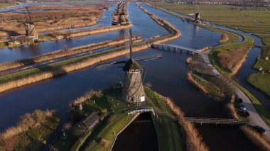 Kinderdijk 'in büyüleyici güzelliğine tanık olun. Yel değirmenleri alacakaranlık gökyüzünde zarafetle beliriyor. Siluetleri sakin suları yansıtıyor ve hayranlık uyandıran pitoresk bir manzara yaratıyor..