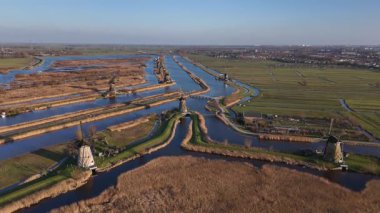 Kinderdijk 'in üzerine alacakaranlık çökerken ikonik yel değirmenleri alacakaranlık gökyüzüne karşı dimdik dururlar. Yansımalar sakin sularda dans eder, zamansız bir Hollanda güzellik ve dinginlik manzarası sergiler..
