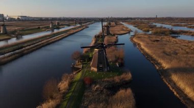 Alacakaranlık çöktüğünde Kinderdijk 'in ikonik yel değirmenleri sakin bir manzaraya karşı dimdik dururlar. Sakin sular solan ışığı yansıtıyor ve Hollanda 'da büyülü bir atmosfer yaratıyor..