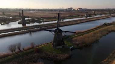 Gün geçtikçe, sakin güzellik Kinderdijks 'in ikonik yel değirmenlerini kaplıyor. Yansımalar dingin sularda dans ederken gökyüzü alacakaranlığa dönüşüyor ve büyülü bir atmosfer yaratıyor..