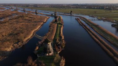 Alacakaranlık Kinderdijk 'i sararken ikonik yel değirmenleri ufukta dikiliyor. Su nazikçe akar, bu tarihi yapıların siluetini yansıtır. Doğanın sükuneti arasında..