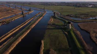 Kinderdijk yel değirmenlerinin büyüleyici siluetine tanık olun. Karanlık gökyüzüne karşı zarif bir şekilde duruyorlar. Sakin su yolları güzelliklerini yansıtıyor, büyülü bir ortam yaratıyor..