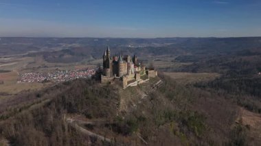 Hechingen yakınlarındaki güzel kırsal bölgede yükselen görkemli Hohenzollern Kalesi 'ni keşfedin. Etrafı yemyeşil dağlarla çevrili olan tarihi mekan açık mavi gökyüzünün altında parlak bir şekilde parlıyor..
