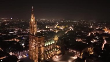 Göz kamaştırıcı ışıklar, gece gökyüzüne karşı Strazburg 'lu Hanımefendimizin Katedrali' ni aydınlatıyor. Eski mimari görkemli bir şekilde dururken şehir altta parıldıyor ve büyüleyici bir atmosfer yaratıyor..