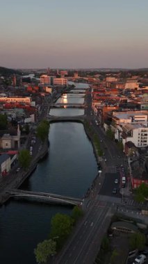 Alacakaranlık çökerken Cork 'un çarpıcı hava manzarasını deneyimleyin. Huzurlu Lee Nehri, şehrin canlı mimarisi ve yeşilliğini ortaya çıkaran ılık akşam parıltısını yansıtır..
