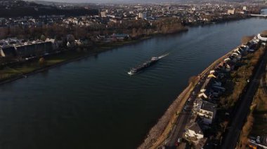 Altın renkler, Koblenz 'deki Ren Nehri' nin sakin sularında zarifçe gezinen bir mavna gibi manzarayı kucaklıyor. Çarpıcı şehir silüeti batan güneşle aydınlanır..