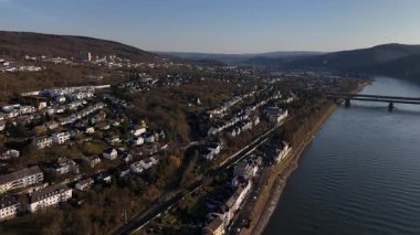 Güneş Koblenz 'in üzerinde batarken, Ren Nehri boyunca süzülen sakin bir mavna şehrin canlı renklerle dengelenmiş güzel bir manzarasını sunuyor..