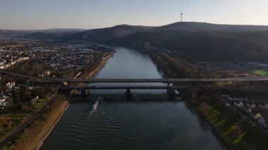 Güneş batarken, sakin bir mavna Koblenz yakınlarındaki Ren Nehri 'nin akan sularında yol alır. Şehrin silueti, canlı gökyüzüne karşı güzelce zıt düşüyor..