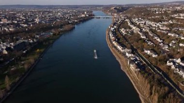 Güneş batarken, Ren Nehri boyunca Koblenz 'in büyüleyici manzarasıyla çevrili huzurlu bir mavna süzülüyor. Alacakaranlık, sakin sulara ve yemyeşil kıyılara büyülü bir ışık saçıyor..