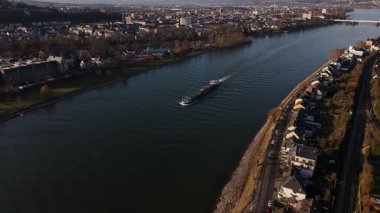 Güneş Koblenz 'ın üzerinde batarken, huzurlu bir mavna Ren Nehri' nin dingin sularında geziniyor, büyüleyici nehir kenarı evleri ve alacakaranlık narin parıltısıyla çevrili..