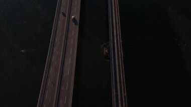 Koblenz 'daki büyüleyici akşam atmosferini yaşayın arabalar geçerken ve bir tren Ren Nehri üzerindeki görkemli köprüyü geçerken, sakin sularla çevrili, alacakaranlık gökyüzünü yansıtan.