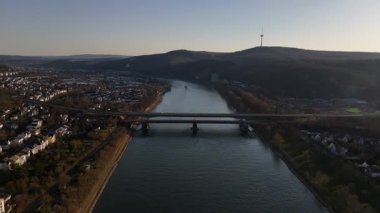 Altın saat Ren Nehri 'nin üzerine sıcak bir parıltı saçarken Koblenz' in göz kamaştırıcı manzaraları dönüşüyor. Şehir silueti, köprüler ve yemyeşil tepeler resim gibi bir akşam manzarasıyla birleşir..