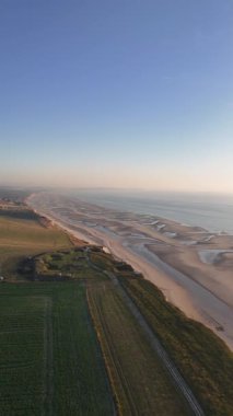 Normandiya 'da güneş batarken Fransız kuzey kıyılarının huzurlu güzelliğinin tadını çıkarın. Altın saat, kumlu sahilleri ve yumuşak dalgaları vurguluyor, barışı ve yansımayı davet ediyor..