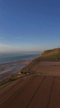 Altın saatin gökyüzünü yumuşak renklerle boyadığı Fransa 'nın kuzey kıyı şeridinin dingin güzelliğini keşfedin. Yumuşak dalgalar kıyıları öperek Normandiya manzaraları boyunca huzurlu bir atmosfer yaratır..