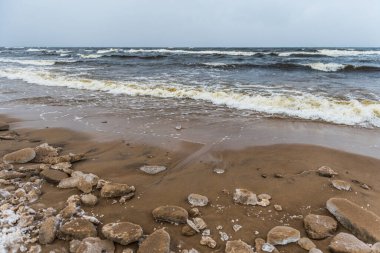 Baltık Denizi karlı plajı, kışın denizde dalgalar, Letonya Saulkrasti 'de