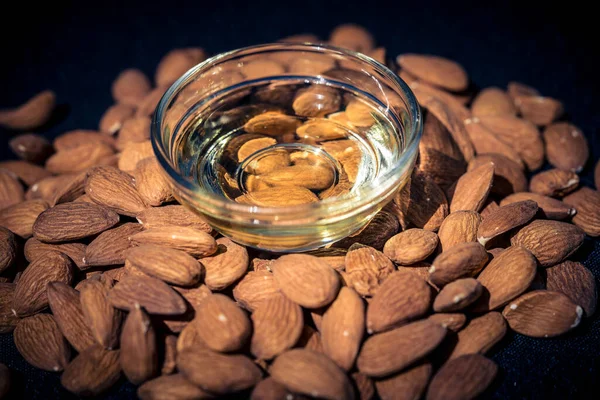 a pile of almonds and a glas with almond oil