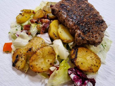 Kızartma tavasından taze kızarmış biftek ve lezzetli malzemeler.