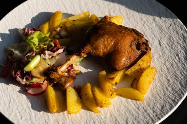 Kızarmış ördek bacağı, salata ve patates.