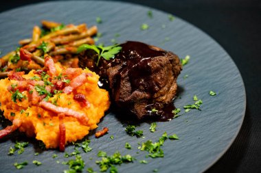 Tatlı patates püresiyle dana yanakları ve domates soslu fasulye ve sarımsaklı pastırma.