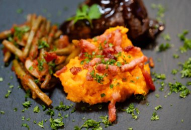 Tatlı patates püresiyle dana yanakları ve domates soslu fasulye ve sarımsaklı pastırma.