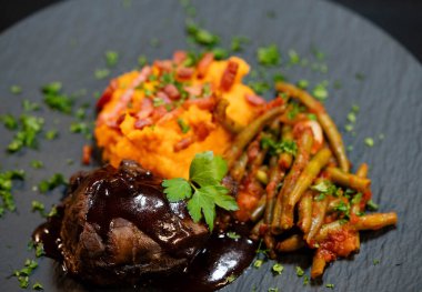 Tatlı patates püresiyle dana yanakları ve domates soslu fasulye ve sarımsaklı pastırma.