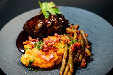 Tatlı patates püresiyle dana yanakları ve domates soslu fasulye ve sarımsaklı pastırma.