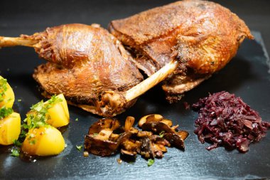 Kızarmış kaz ve patates, kırmızı lahana, yabani mantar ve kahverengi sos.