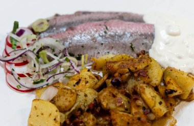 Kızarmış patates ve Sylt soslu taze sebze matjeleri.