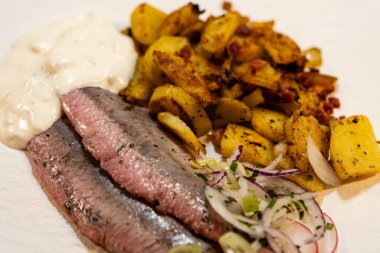 Kızarmış patates ve Sylt soslu taze sebze matjeleri.