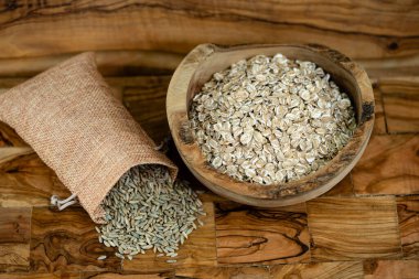 whole grain Secale cereale rye flakes on olive wood