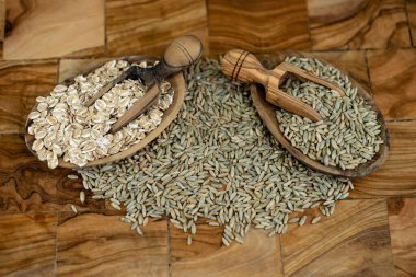 whole grain Secale cereale rye flakes on olive wood