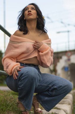 Nehrin kıyısında kazaklı, topuklu ayakkabılı, kot pantolonlu ve yumuşak tenli güzel bir kadın.