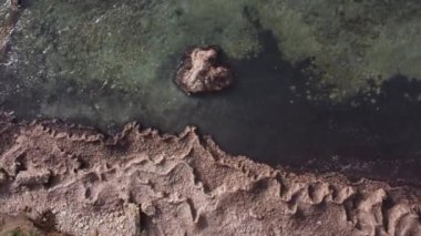Taşlı ve kristal berrak zümrüt suyla dalgalı deniz dalgalarının üst drone görüntüsü