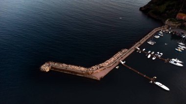 Kayalar ve kristal berrak zümrüt suyu ile sakin deniz dalgalarının en üst düzey drone görüntüsü, Toskana 'da Porto Ercole kasabası manzarası, İtalya günbatımı