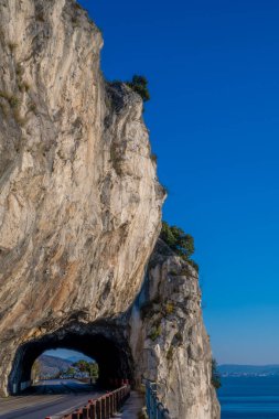 Passage tunnel under the mountain for cars, at the edge of the coast of Trieste Italy. Adriatic sea and surrounding trees.