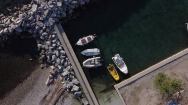 Video of boats, fishing boats moored in a small port. Calm and crystalline sea, beach and rocks.